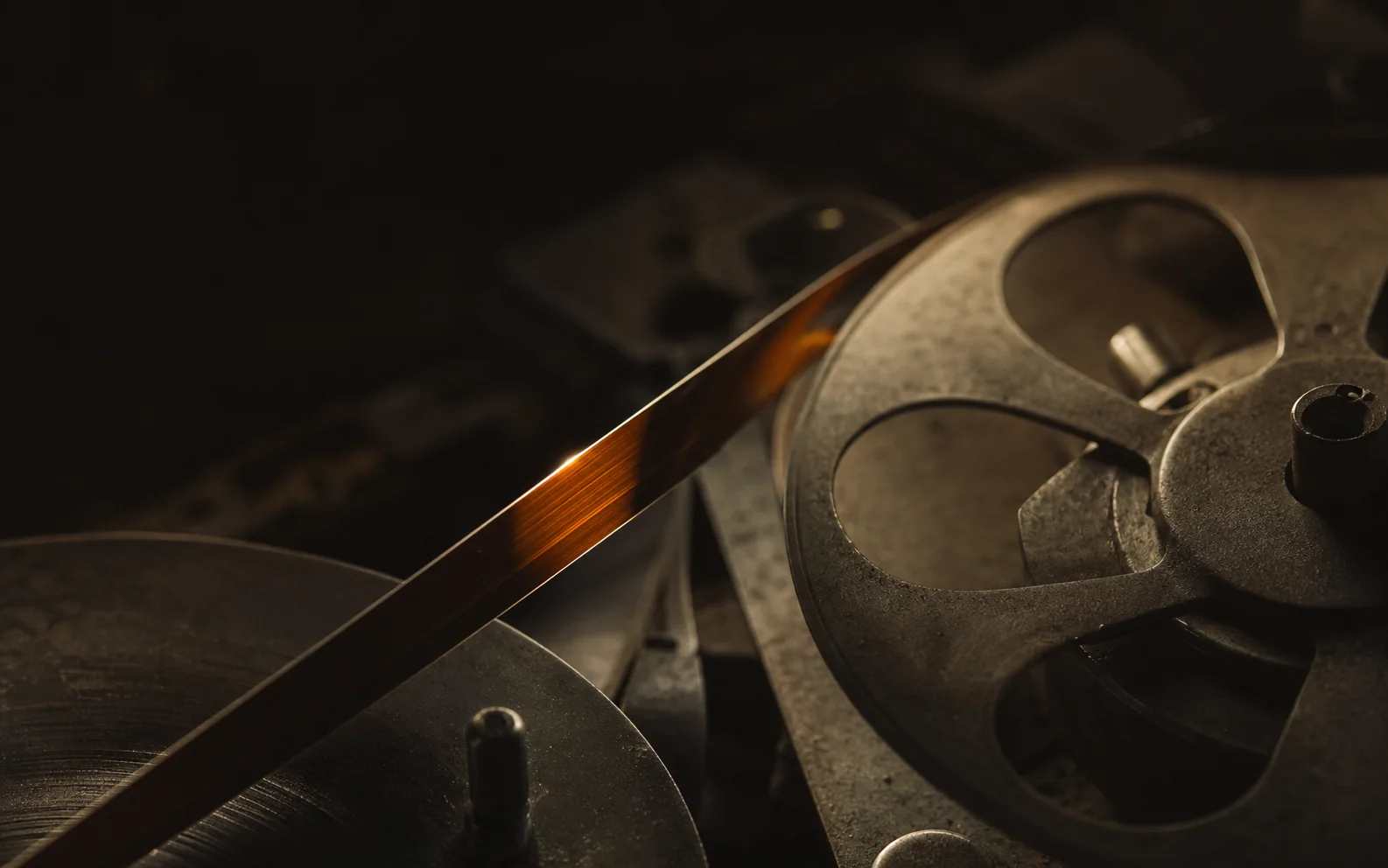 Amber magnetic tape crossing dark metal recording reels
